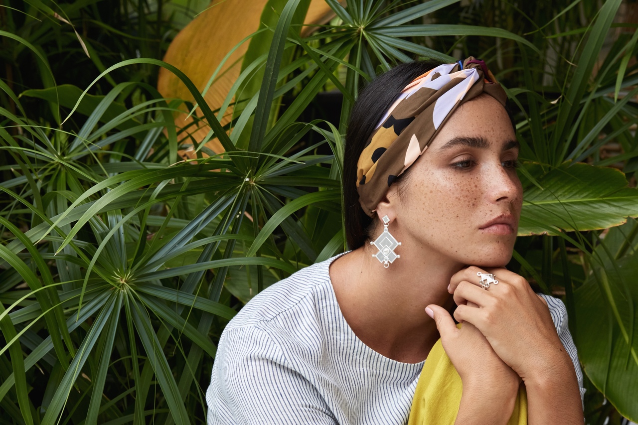 Portrait de femme portant des boucles d'oreille de profil avec des plantes en arrière-plan